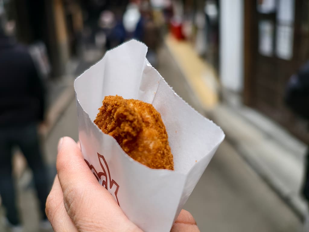 スマホで撮影した、冬の有馬温泉で、コロッケを食べ歩きしている写真